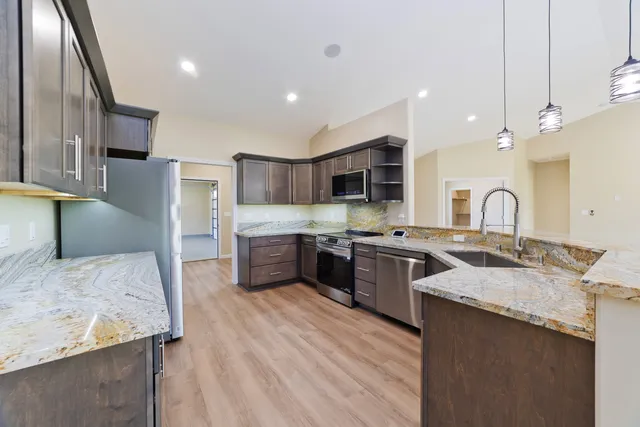 a large kitchen with stainless steel appliances granite countertop a sink a stove and a refrigerator