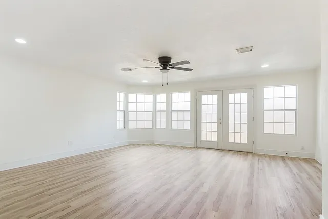 an empty room with wooden floor and windows