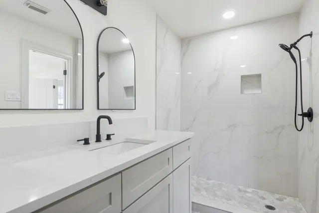 a bathroom with a sink a mirror a vanity and shower