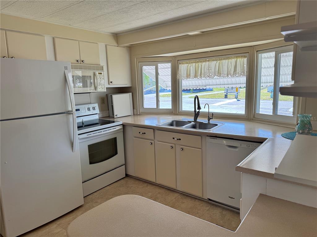 1891 Englewood Road, Unit 45 Englewood, FL 34223 - Photo 11 of 55 a kitchen with a sink white cabinets and white appliances