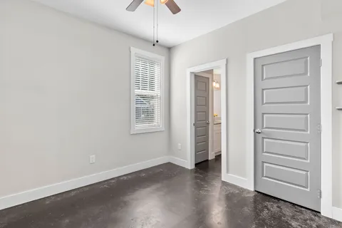 an empty room with wooden floor closet and windows