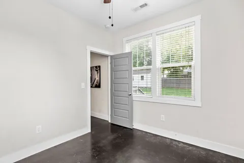 an empty room with wooden floor and windows