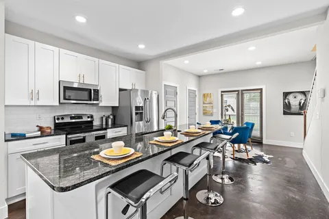 a kitchen with stainless steel appliances granite countertop a stove refrigerator and dining table with wooden floor