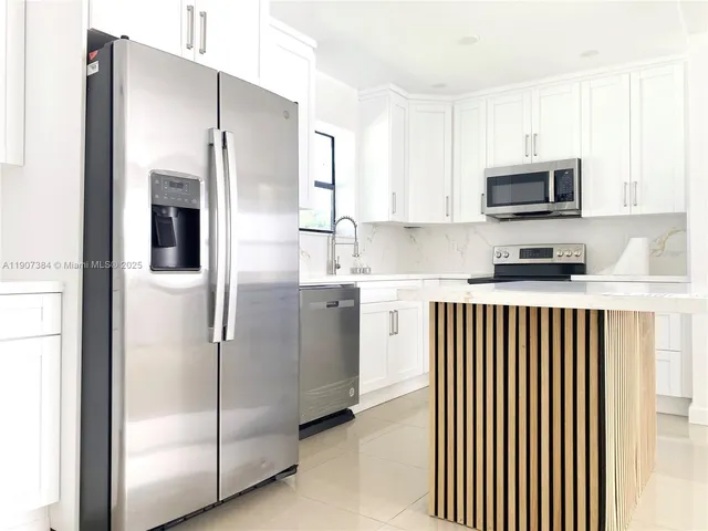 a kitchen with stainless steel appliances granite countertop a refrigerator and a stove top oven