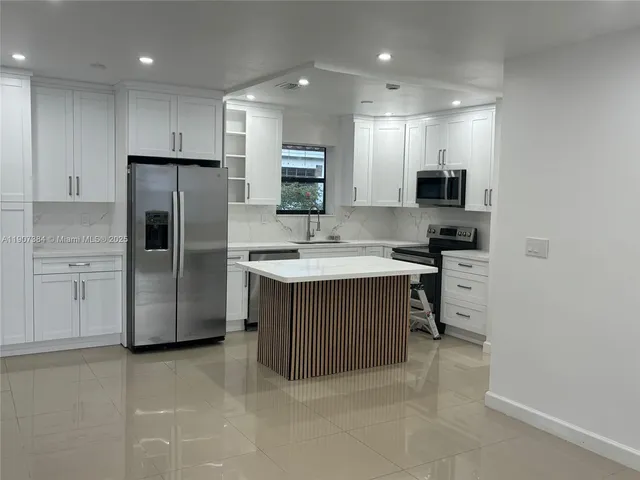 a kitchen with kitchen island a sink stainless steel appliances and cabinets