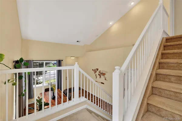 a view of staircase with lots of frames on wall and a large window