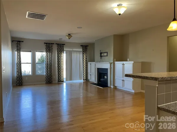 a view of an empty room with wooden floor and a fireplace