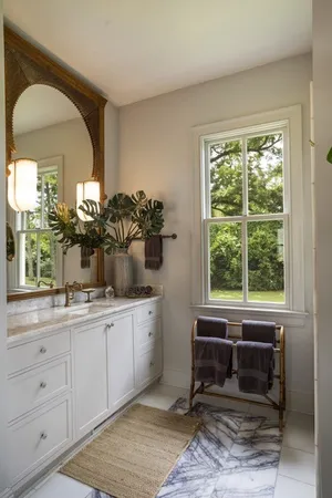a bathroom with a two sinks a large mirror and a window