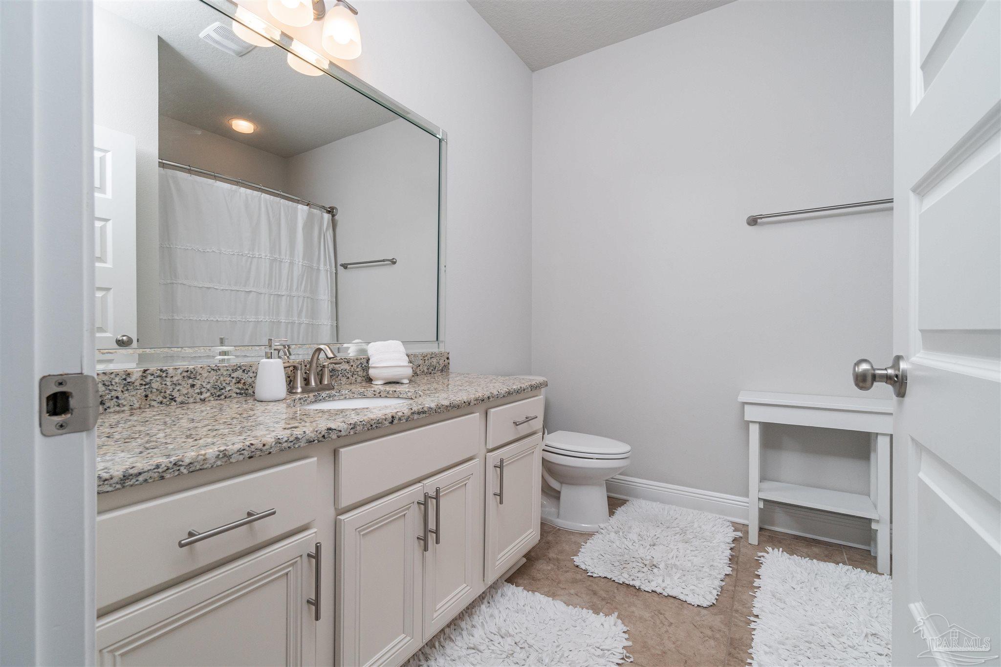 7997 Woodbrook Road Pensacola, FL 32526 - Photo 14 of 35 a bathroom with a granite countertop sink a toilet and a mirror