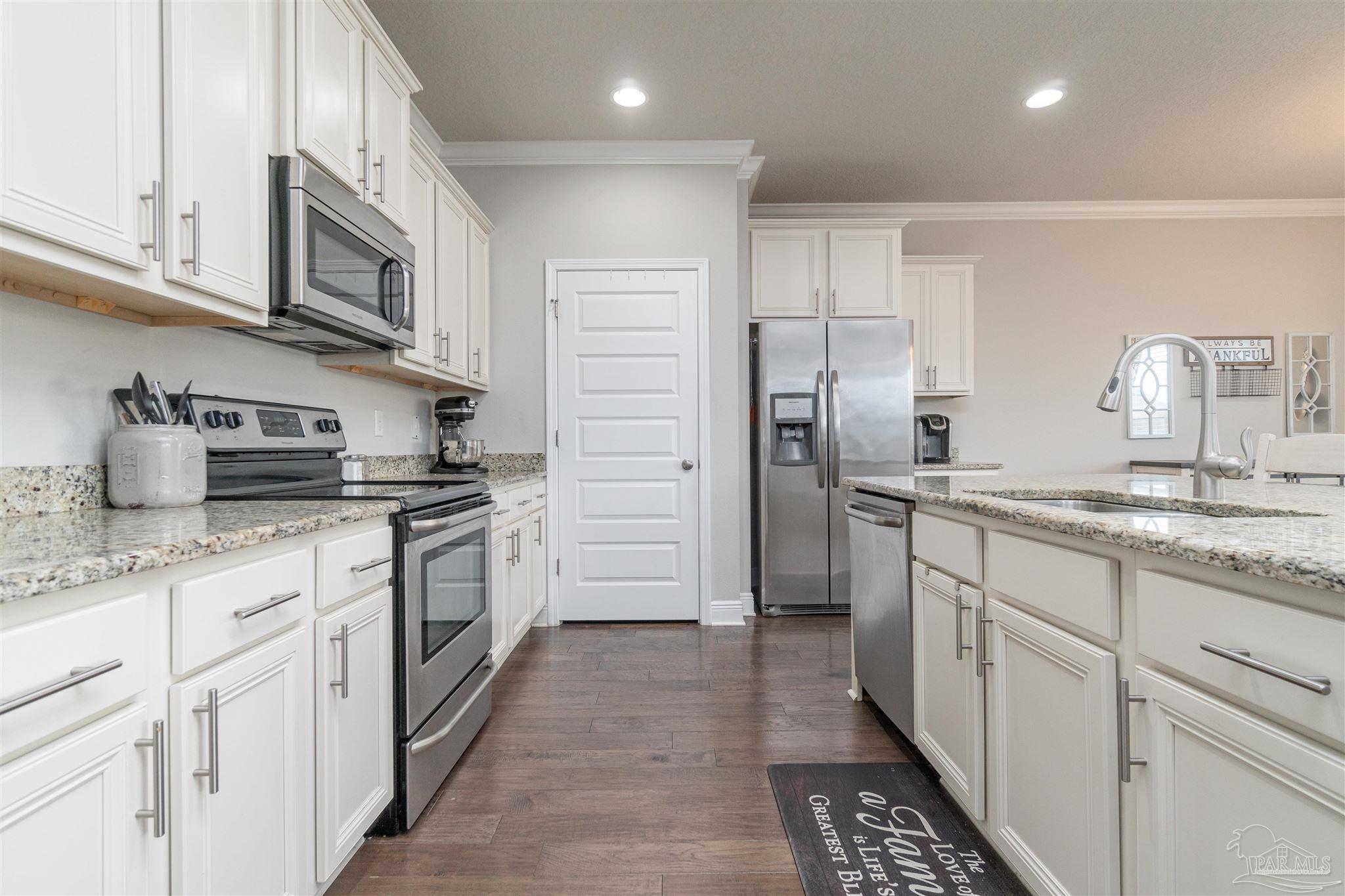 7997 Woodbrook Road Pensacola, FL 32526 - Photo 20 of 35 a kitchen with stainless steel appliances a sink stove refrigerator and cabinets