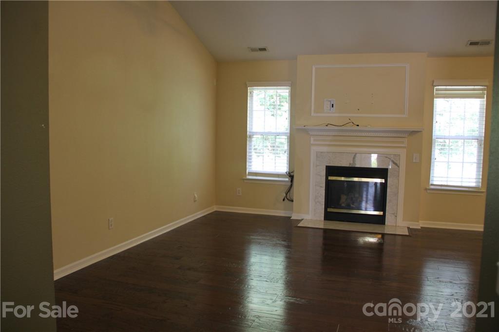 11233 Dickie Ross Road Charlotte, NC 28277 - Photo 5 of 26 an empty room with wooden floor fireplace and windows