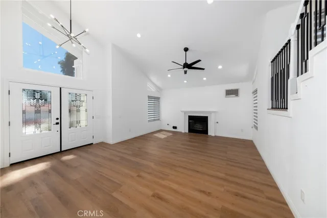 a view of an empty room with wooden floor fireplace and a window