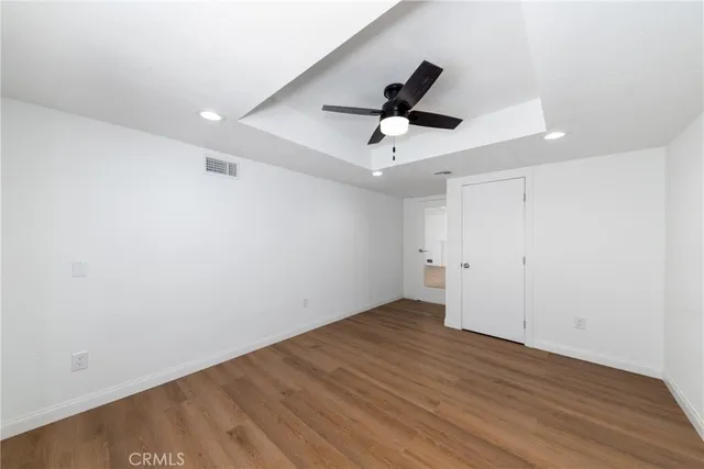an empty room with wooden floor and a ceiling fan