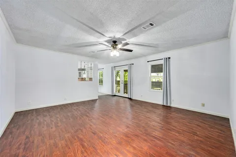 a view of an empty room with window and wooden floor