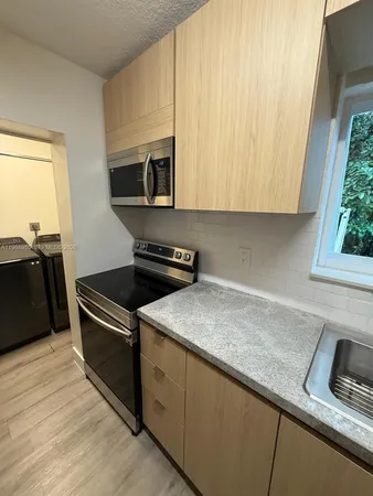 a large kitchen with stainless steel appliances granite countertop a refrigerator and a wooden floor