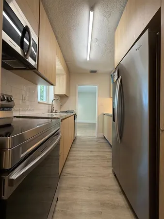 a kitchen with stainless steel appliances kitchen island granite countertop a sink and a microwave