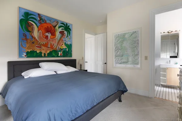 a bedroom with a bed and painting on the wall