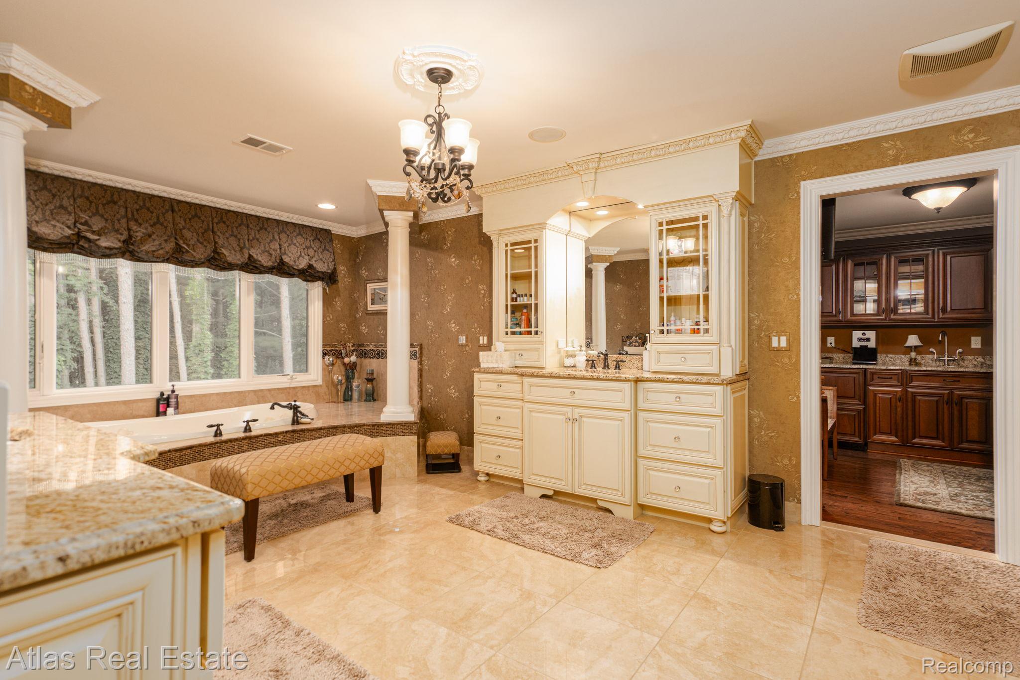 10380 South State Road Goodrich, MI 48438 - Photo 62 of 87 Spacious bathroom featuring a large soaking tub with a tiled surround, a double vanity with built-in cabinetry, and light-toned tile flooring