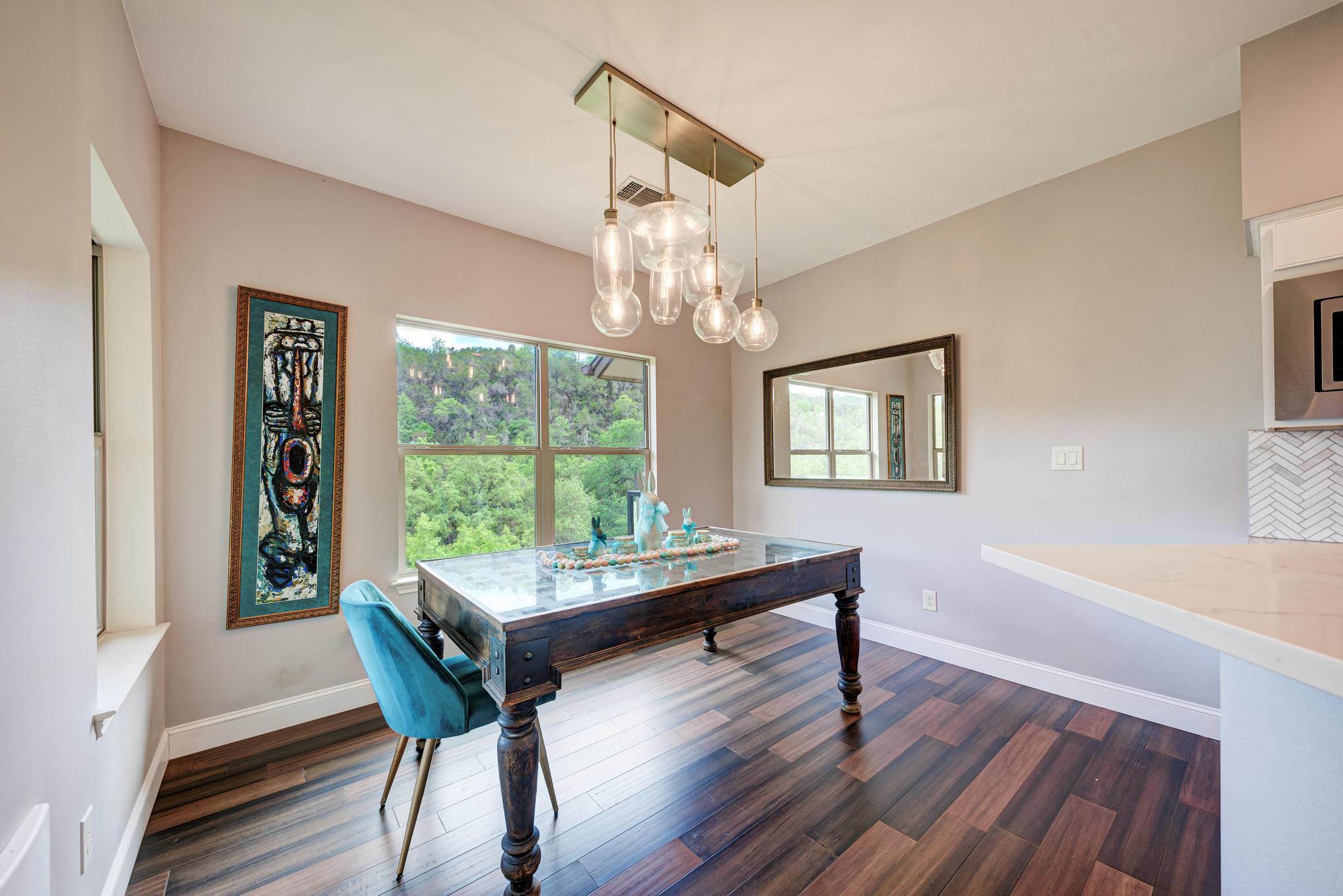 2605 Indian Creek Road Austin, TX 78734 - Photo 10 of 33 Dining area featuring wood-finish flooring, a contemporary multi-light pendant fixture, and a large window overlooking a treed landscape