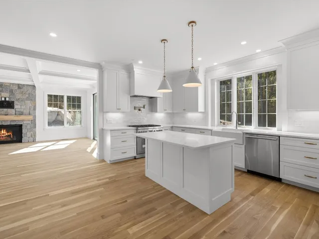 a kitchen with stainless steel appliances granite countertop a sink a stove and a wooden floors
