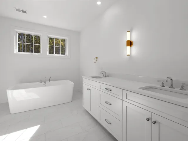 a spacious bathroom with 2 sink bathtub and a mirror