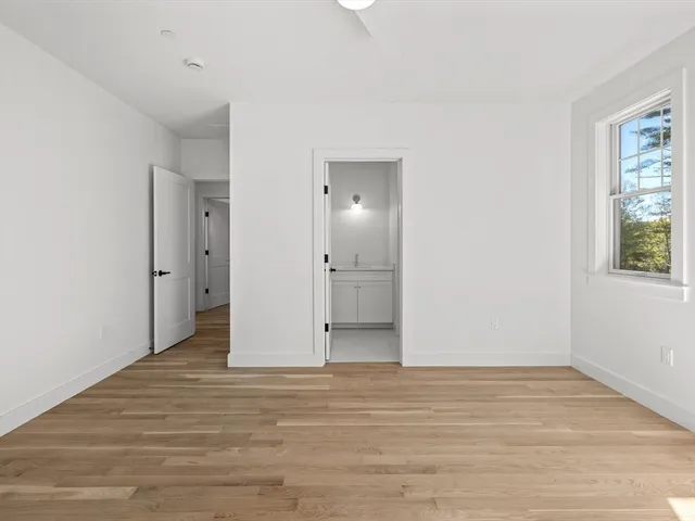 a view of an empty room with window and wooden floor