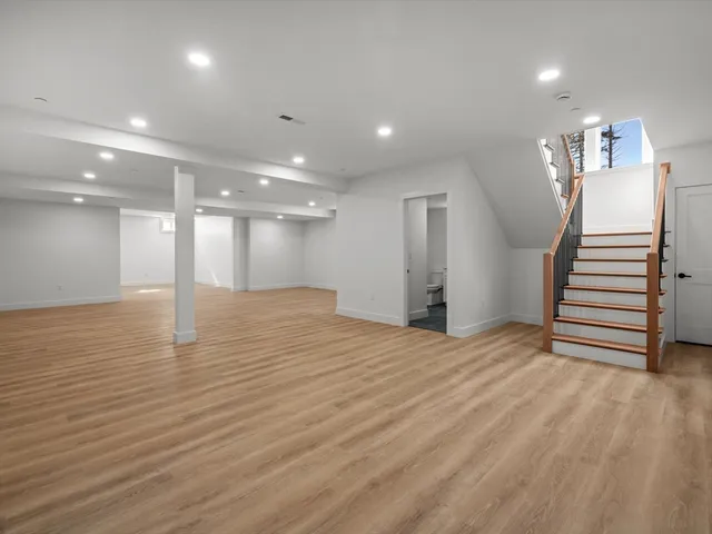 a view of an empty room with wooden floor and stairs