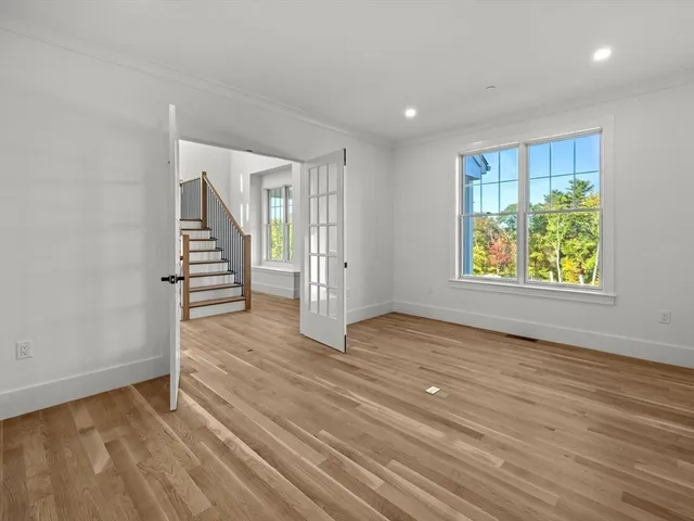 a view of empty room with wooden floor and kitchen view