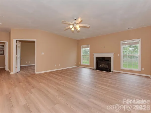 an empty room with windows fireplace and a wooden floor