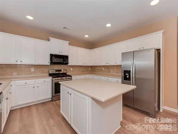 a kitchen with a sink a stove a refrigerator and white cabinets
