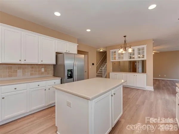 a kitchen that has a lot of white cabinets and wooden floor