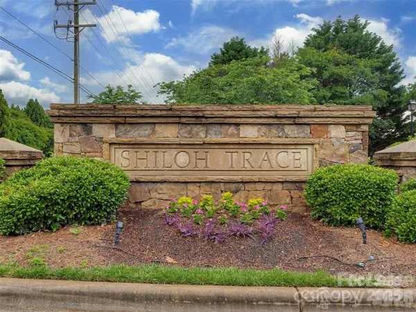 a view of a sign board with a house in the background