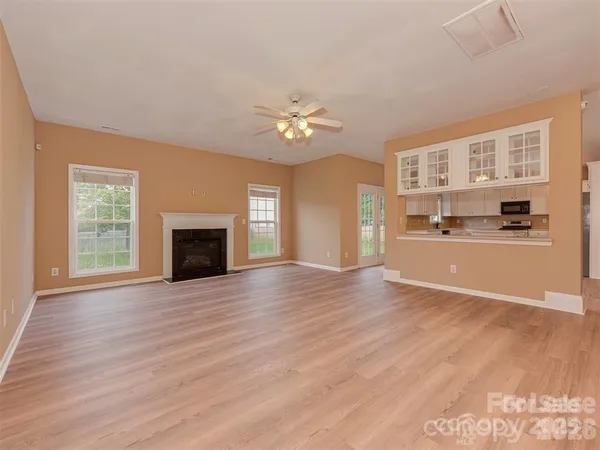 a view of an empty room with a kitchen and a fireplace