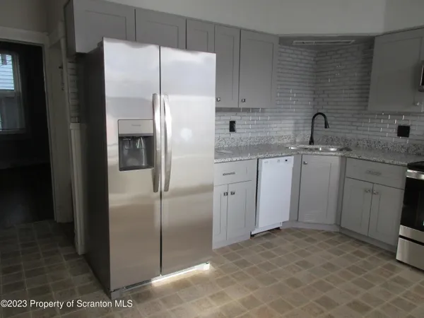 a kitchen with stainless steel appliances granite countertop a refrigerator a sink a stove and white cabinets