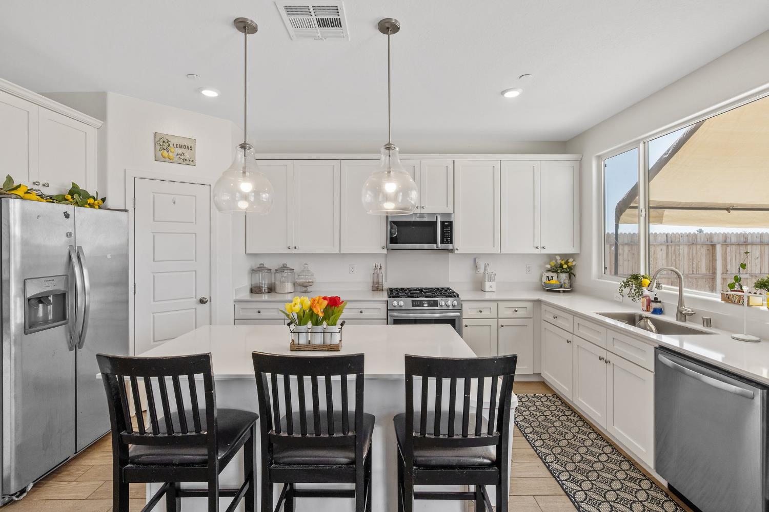 2409 Pepperdine Street Lemoore, CA 93245 - Photo 42 of 50 a kitchen with stainless steel appliances granite countertop a sink a stove a refrigerator with a dining table chairs and cabinets