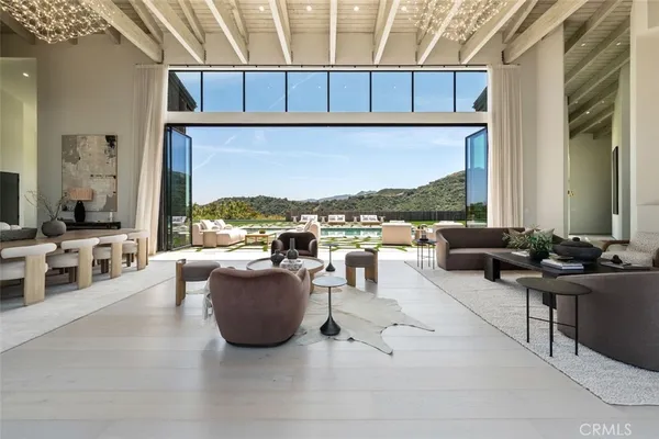 a living room with furniture large windows and wooden floor