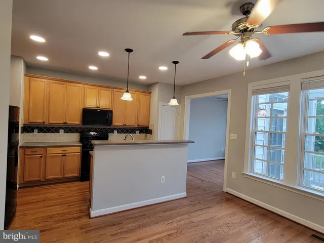 a view of an empty room with wooden floor and fan