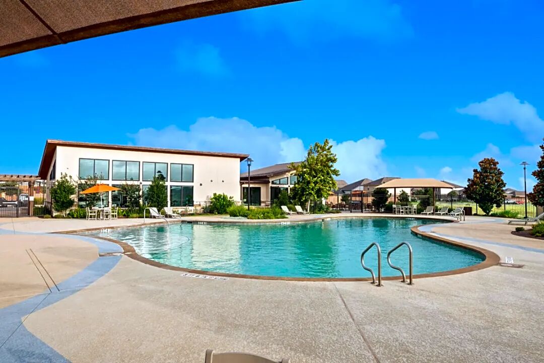 8145 Daisy Cutter Crossing Georgetown, TX 78626 - Photo 24 of 25 Resort-style pool with integrated steps, surrounding concrete decking, and adjacent contemporary clubhouse with expansive windows