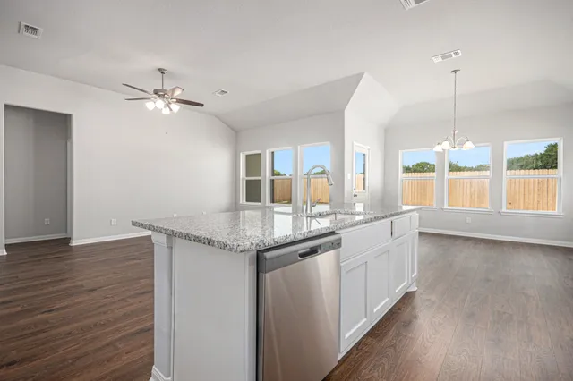 a kitchen with granite countertop a stove a sink and wooden floor