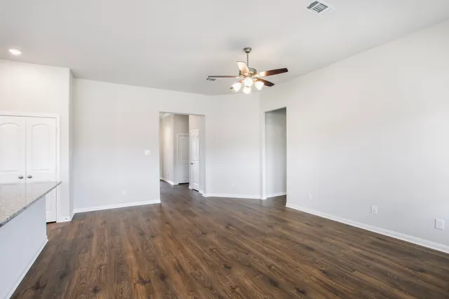 a view of empty room with wooden floor and ceiling fan