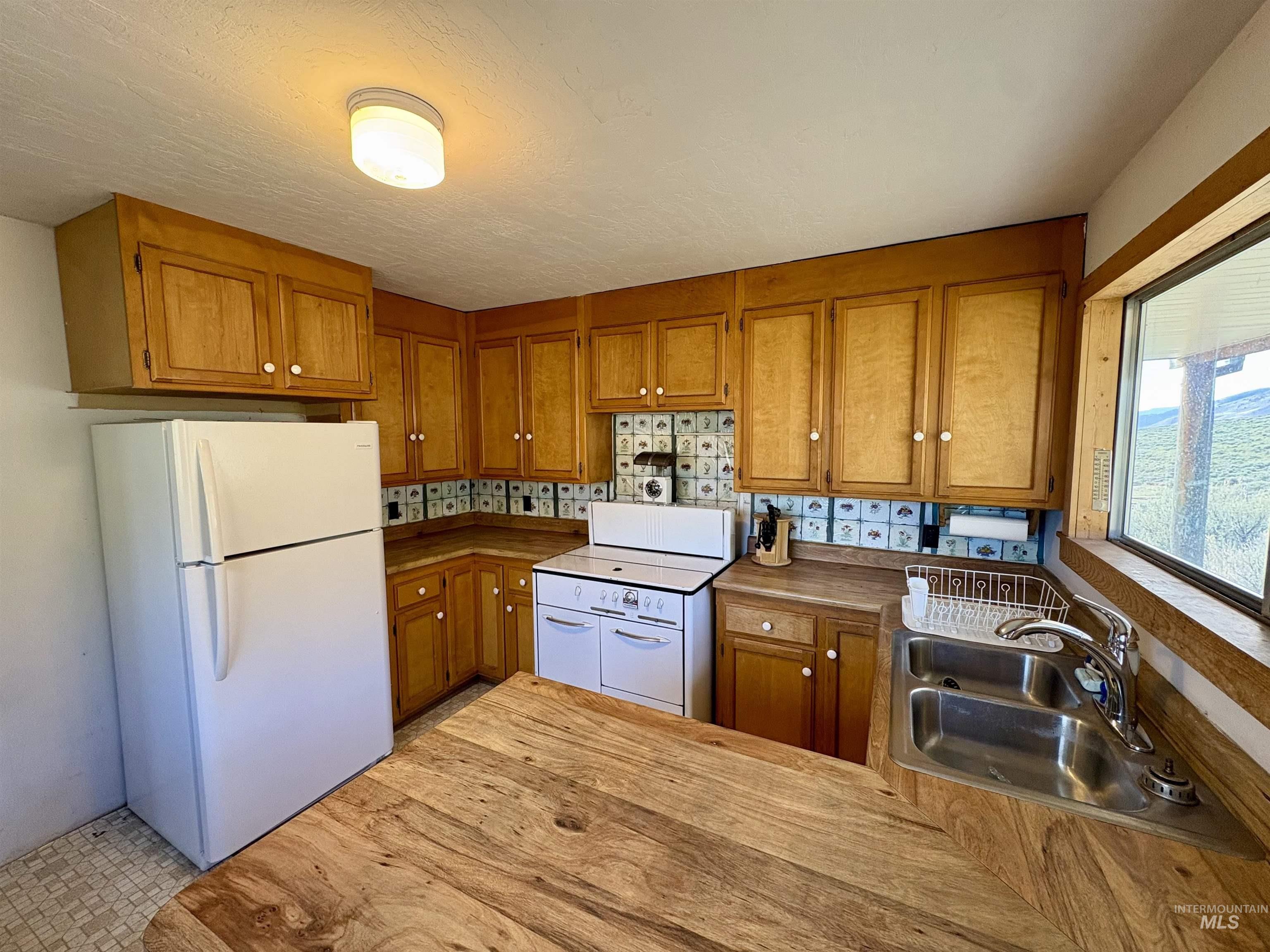 2040 Pahsimeroi River Road May, ID 83253 - Photo 10 of 29 Kitchen featuring wood-finish cabinetry and countertops, a double basin stainless steel sink, a window with exterior visibility, and a ceiling-mounted light fixture
