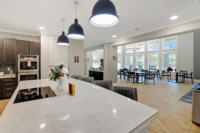 a kitchen with stainless steel appliances a stove a refrigerator a dining table and chairs with wooden floor