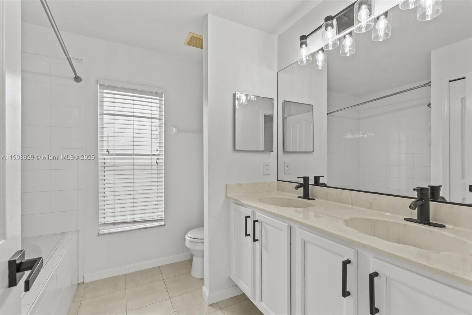 1392 Southwest Sudder Avenue Port St. Lucie, FL 34953 - Photo 14 of 30 a bathroom with a double vanity sink and a mirror