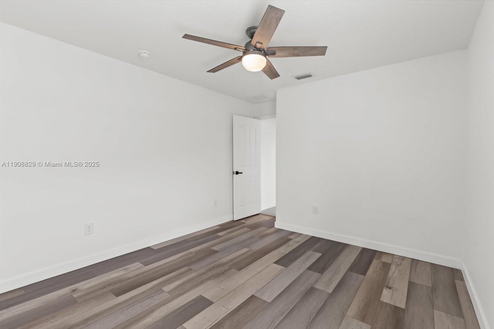 1392 Southwest Sudder Avenue Port St. Lucie, FL 34953 - Photo 20 of 30 an empty room with wooden floor and ceiling fan