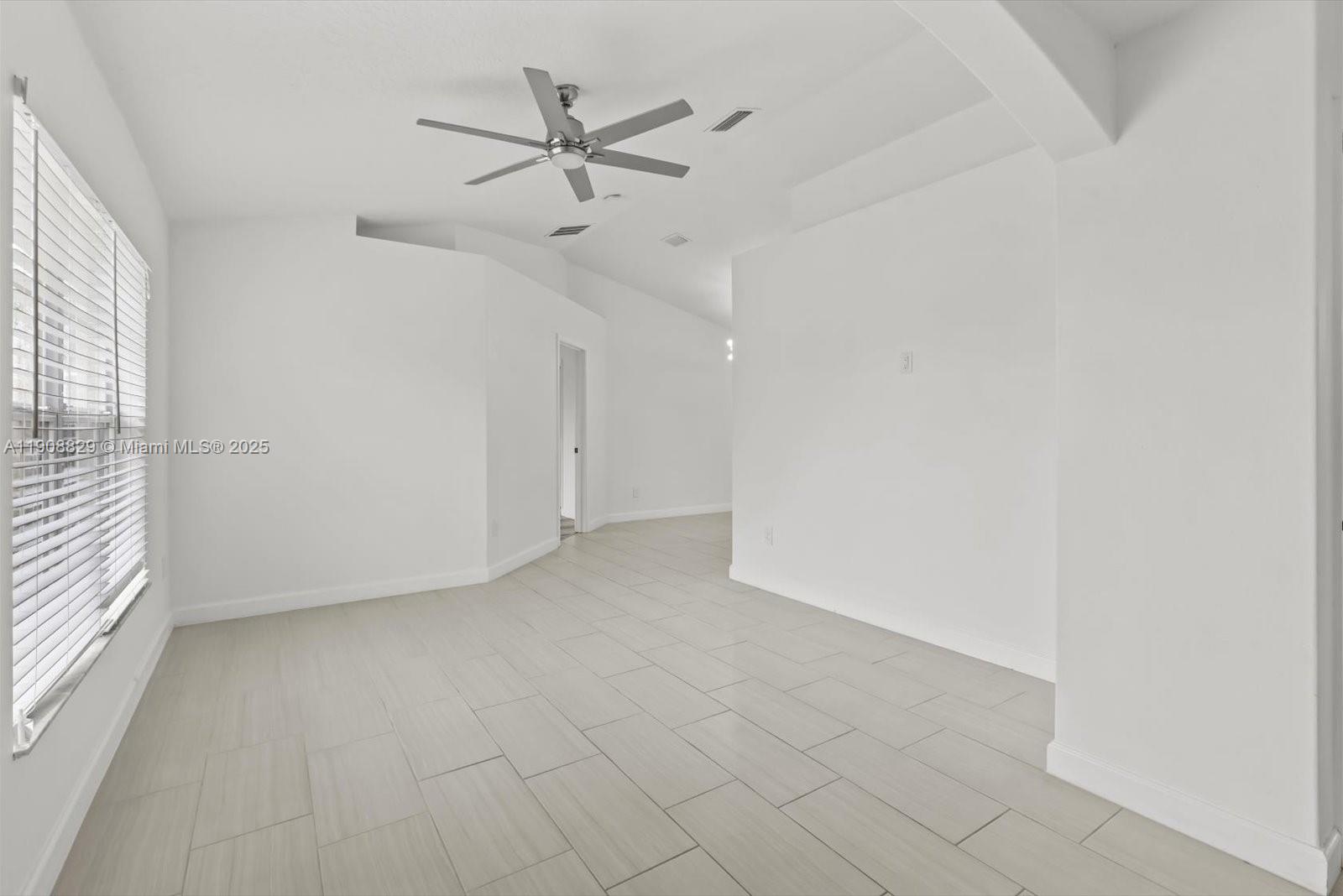 1392 Southwest Sudder Avenue Port St. Lucie, FL 34953 - Photo 3 of 30 an empty room with a ceiling fan and windows
