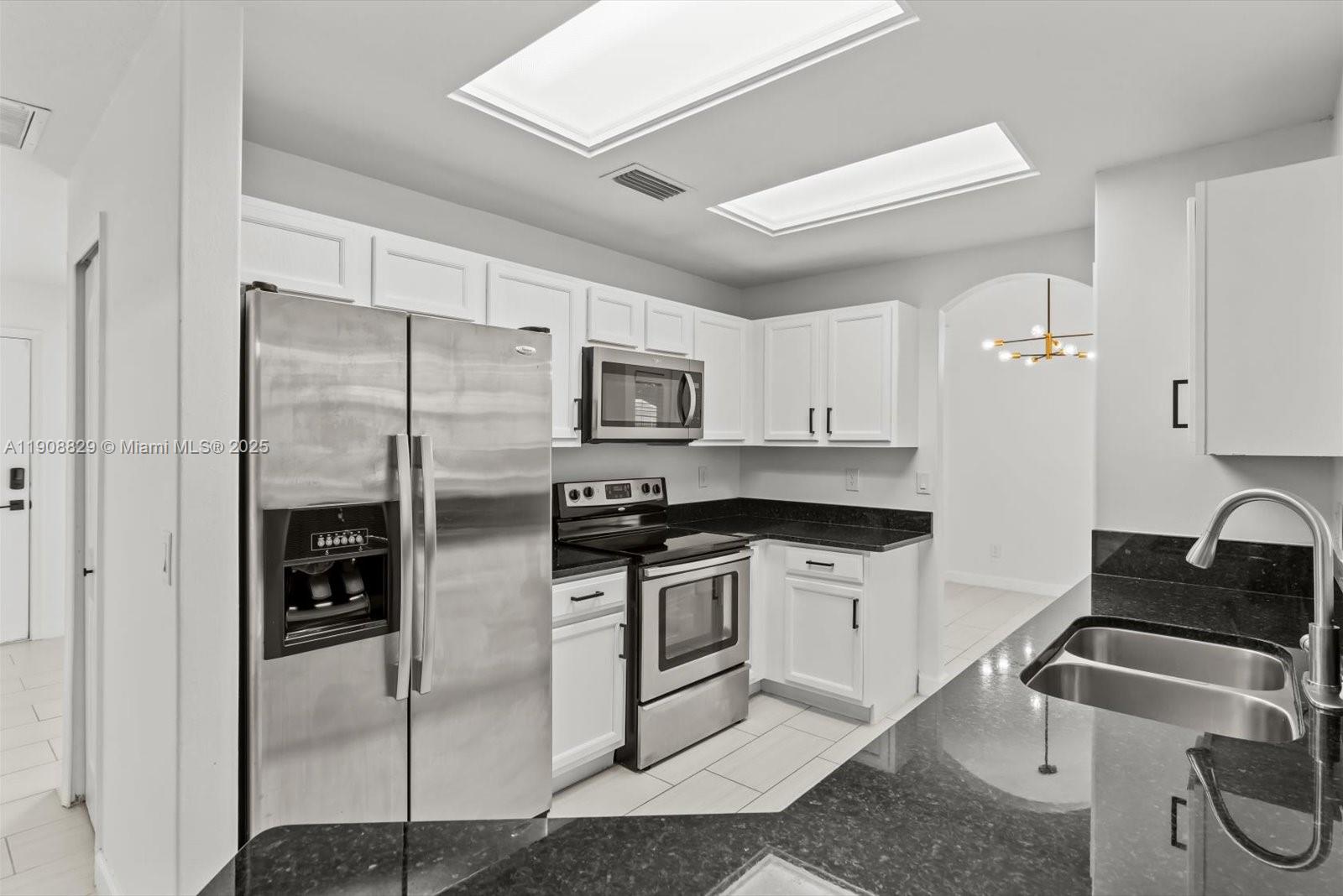 1392 Southwest Sudder Avenue Port St. Lucie, FL 34953 - Photo 9 of 30 a kitchen with stainless steel appliances granite countertop a refrigerator and a stove