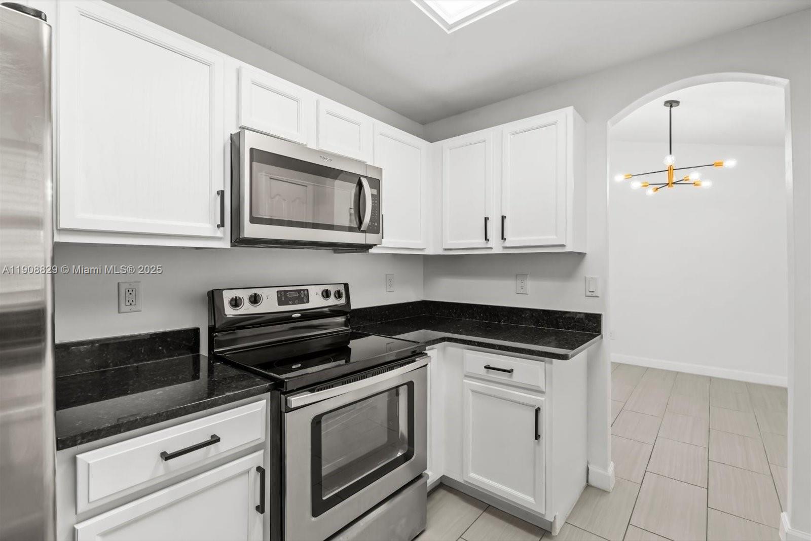 1392 Southwest Sudder Avenue Port St. Lucie, FL 34953 - Photo 10 of 30 a kitchen with granite countertop white cabinets and appliances