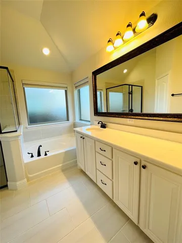 a spacious bathroom with a double vanity sink a mirror and bathtub