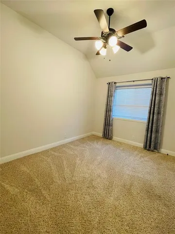 an empty room with a ceiling fan and carpet