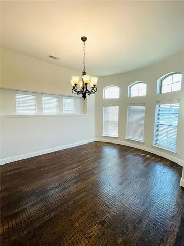 a view of an empty room with wooden floor and windows
